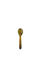 A small olive and amber tortoiseshell-marbled resin spoon with a rounded bowl and short straight handle.